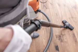 Male Worker Vacuuming Hardwood Flooring.